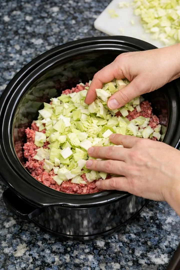 Layer chopped cabbage over raw ground beef, joined by these 3 ingredients, into slow cooker for a hearty dinner that I crave this week after week